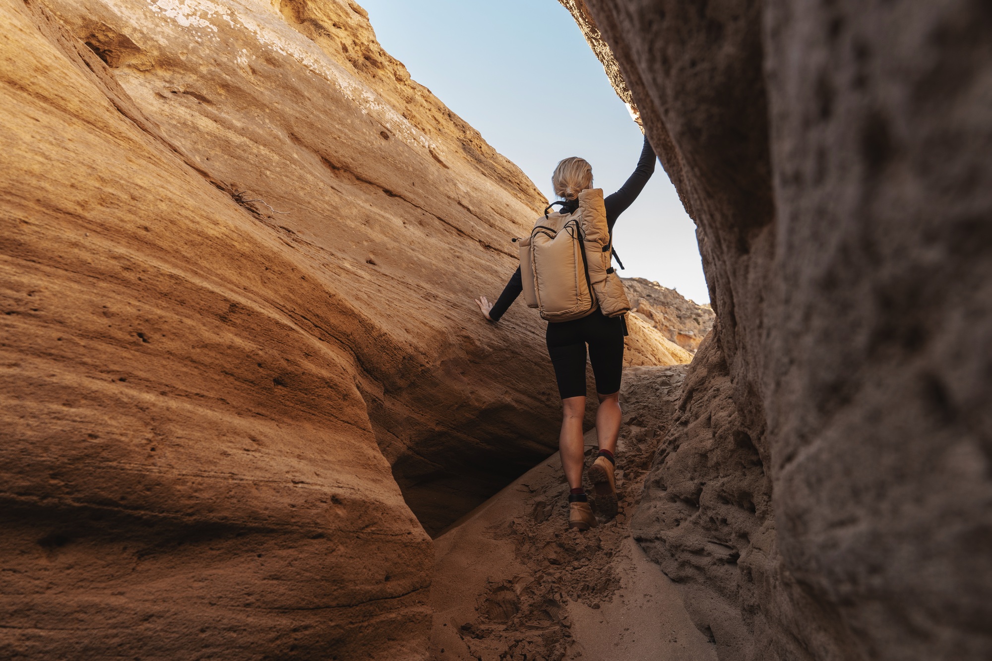 Female hiker exploring a narrow sandstone canyon carrying a backpack with outdoor gear